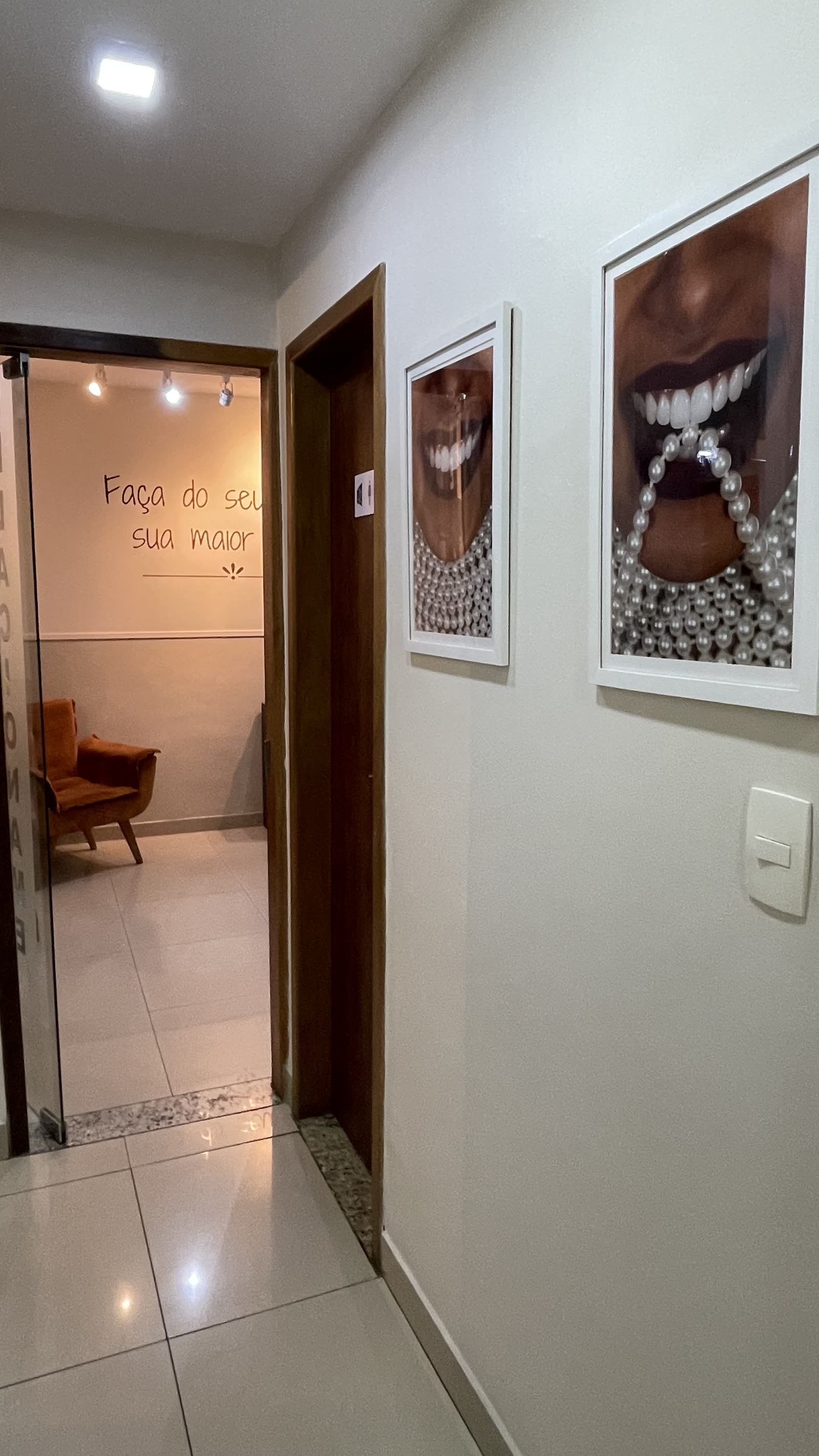 Corredor interno com quadros decorativos e frase inspiradora ao fundo
